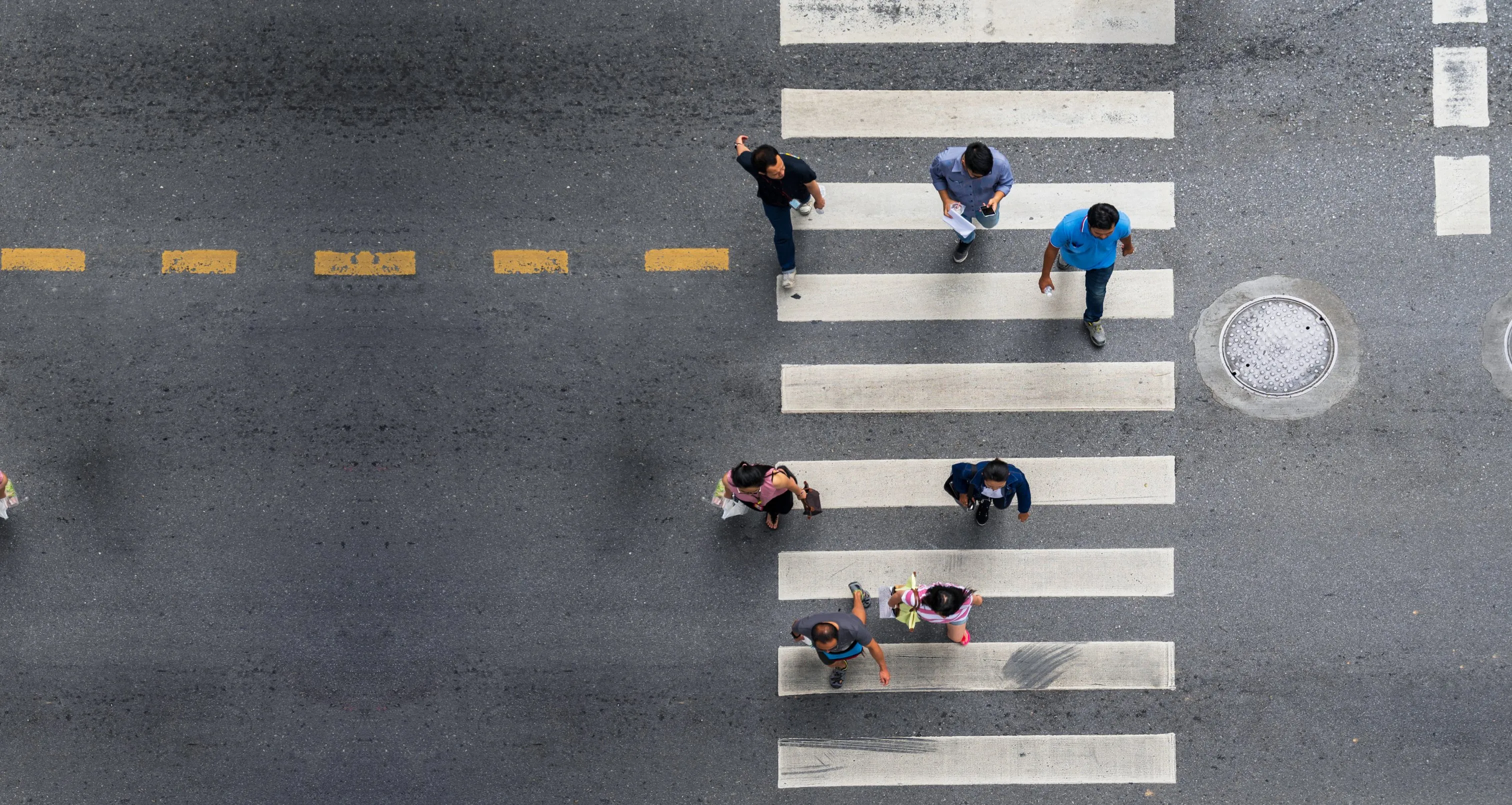 Pedestrians crossing a city crosswalk, seen from above