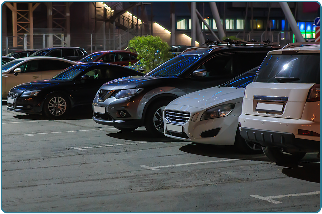Cars parked in a lot at night under a lit building
