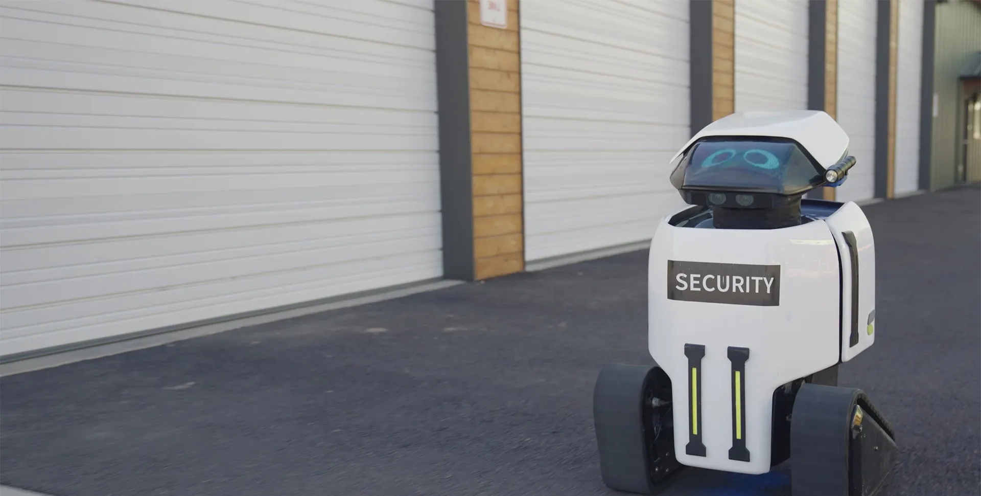 A Dax security robot on patrol beside a row of storage units